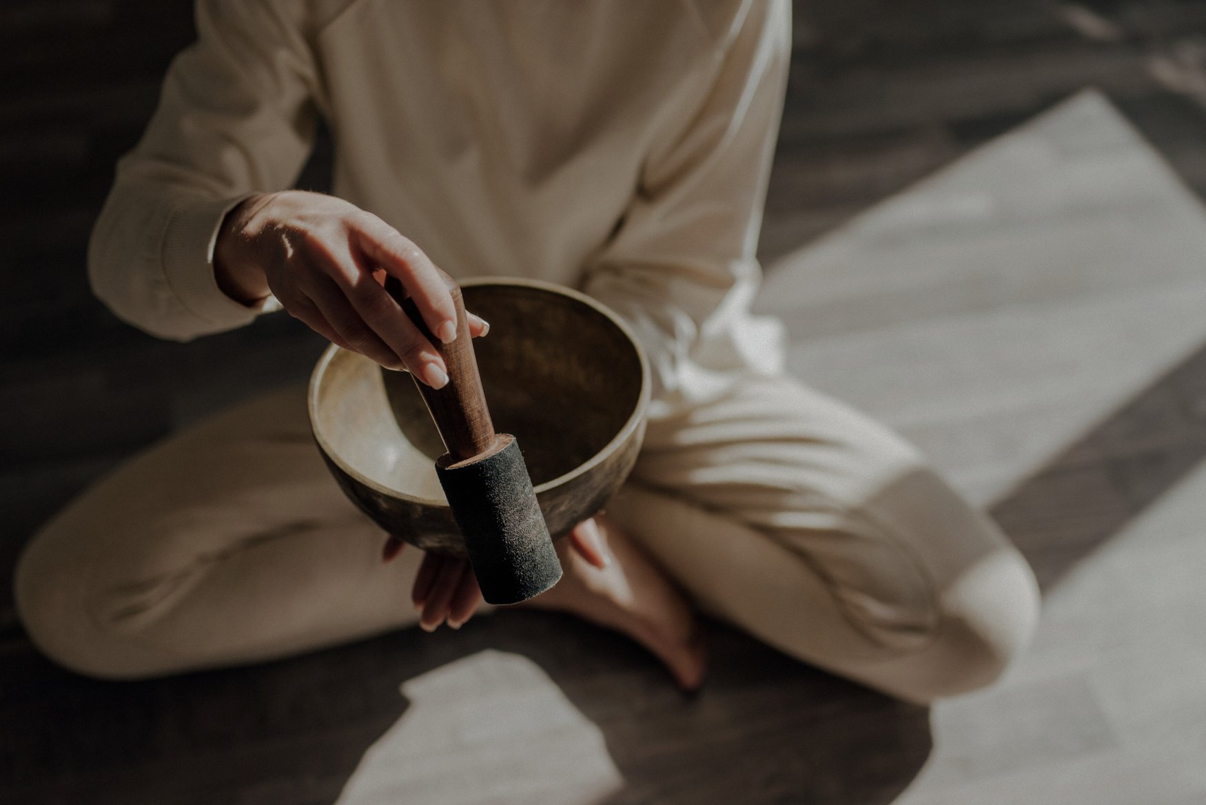 a person sitting on the floor holding a singing bowl