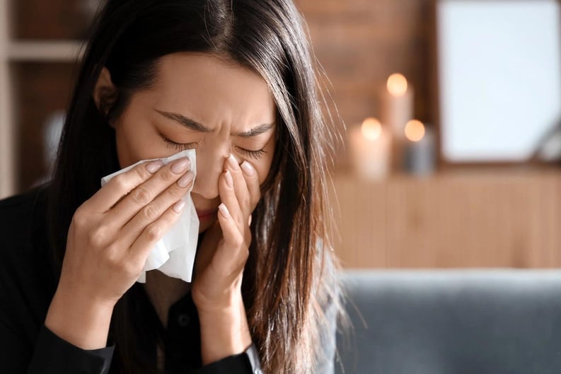 a person blowing their nose while sitting on a couch