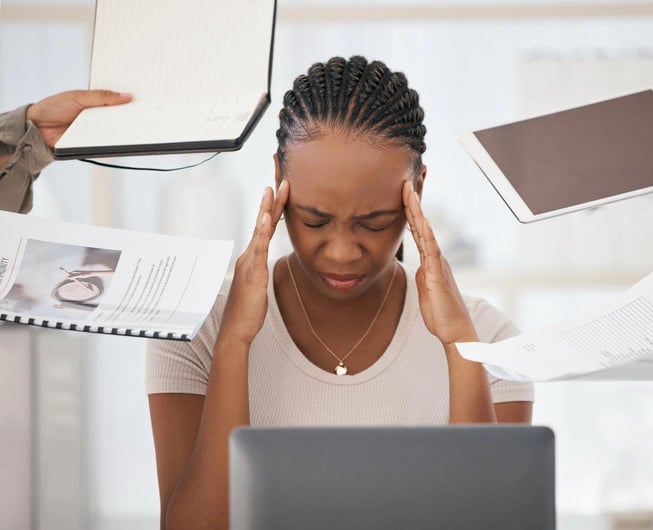 a person sitting at a desk with their head in their hands