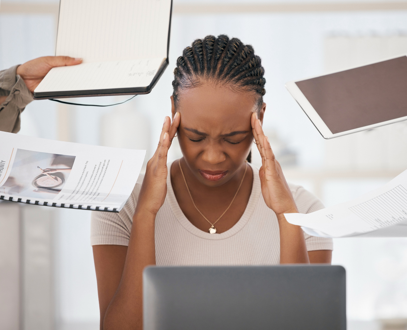 a person sitting at a desk with their head in their hands due to work stress